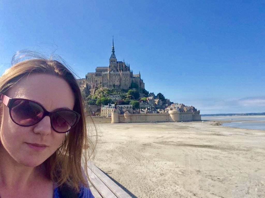 Young woman standing on causeway bridge in front of Mont-Saint-Michel