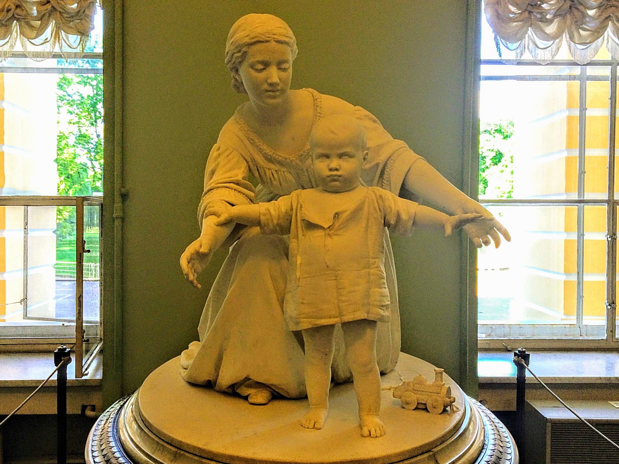 Statue of a mother kneeling behind a newly-walking baby