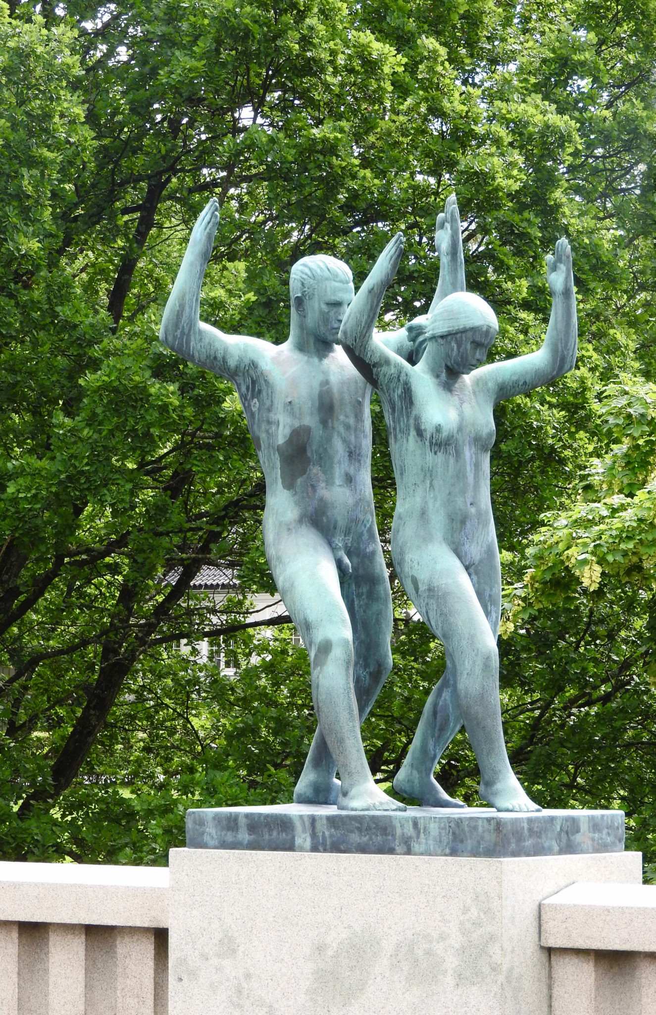 Matching sculptures of a young man and woman standing with knees bent and arms raised