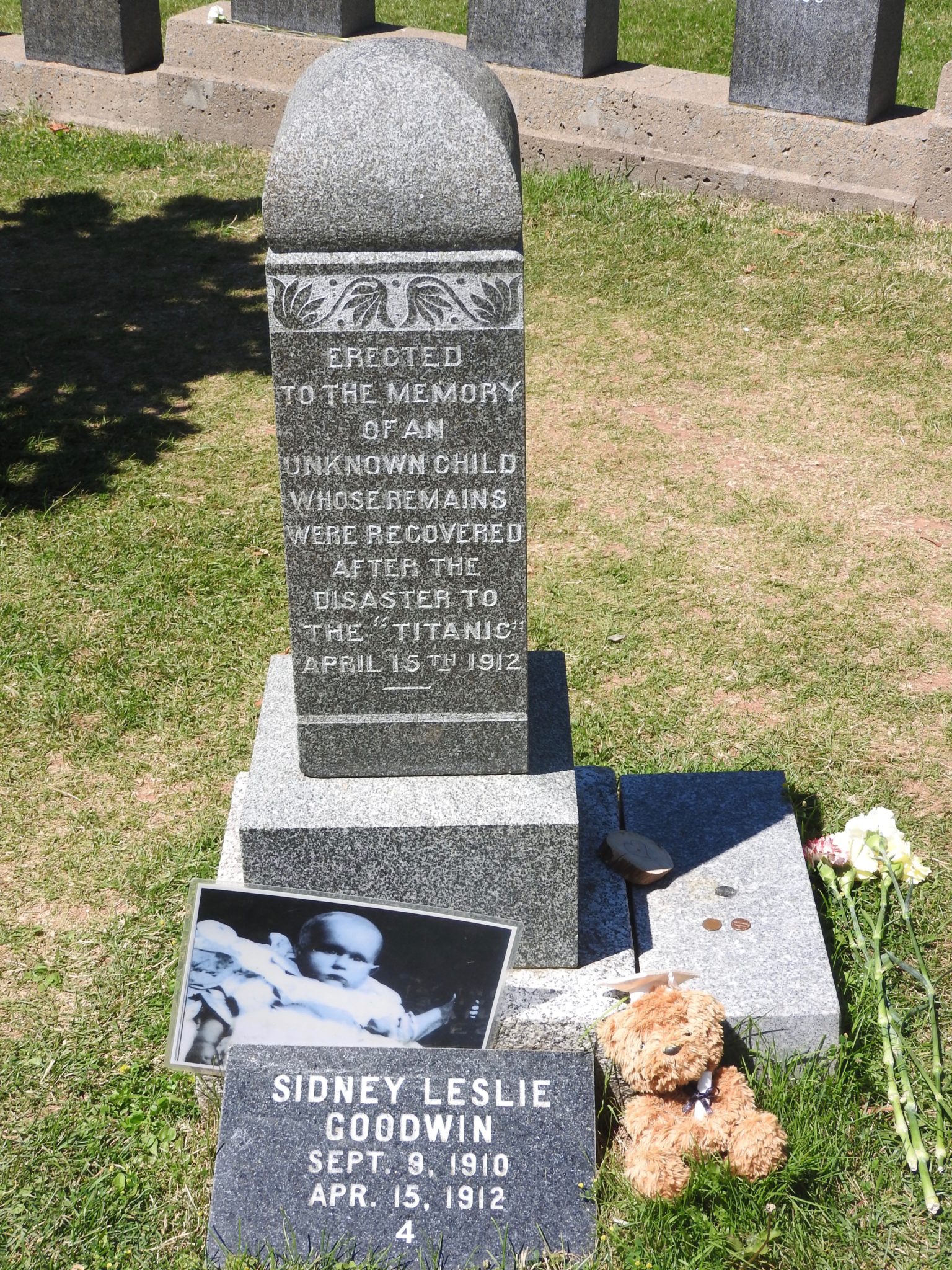 tall headstone with photo and small plaque